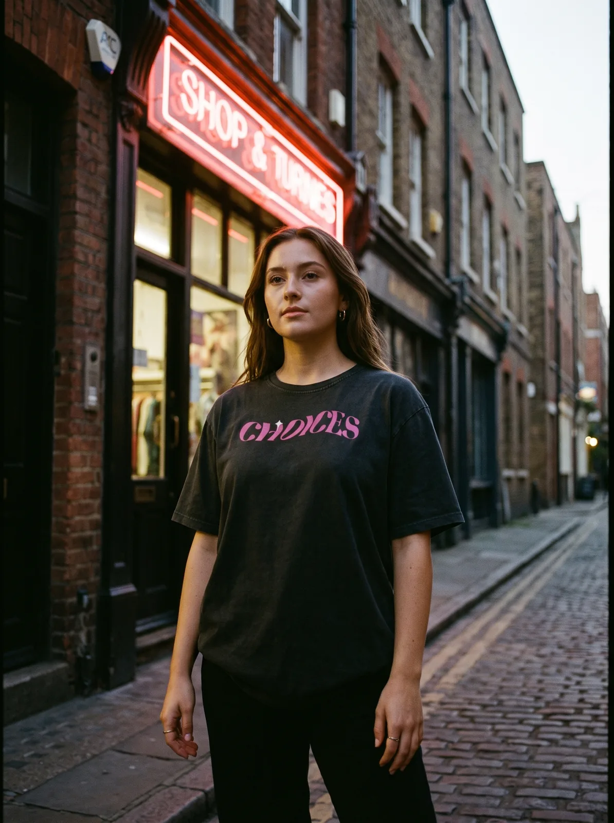 Sunset tee worn facing the camera on a brick street at dusk